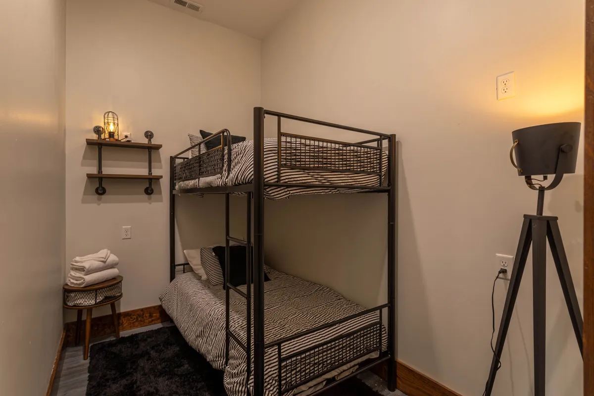 A cheerful interior with a sturdy bunk bed, shelf with playful decor, and a warm lamp, creating a welcoming space ideal for sleepovers and late-night chats. The design is both practical and fun, perfect for kids or young guests.
