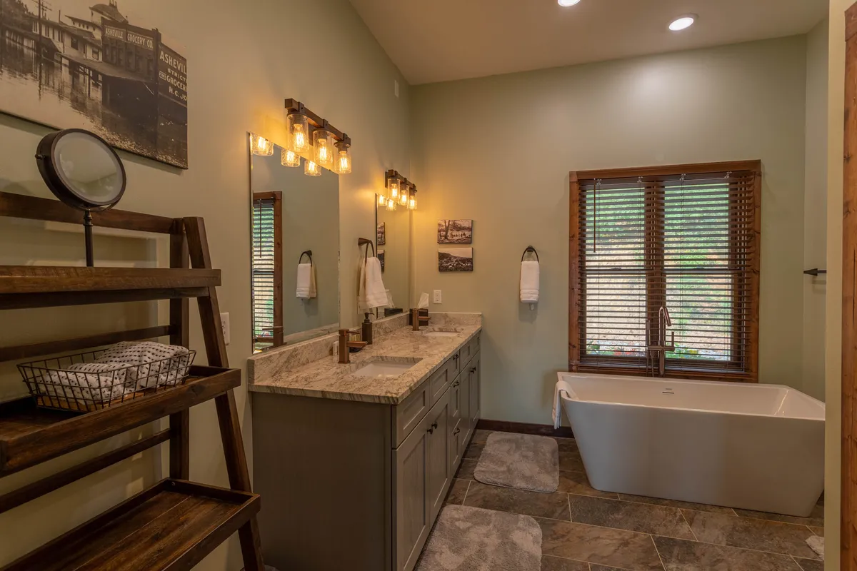A tranquil bathroom space with a luxurious freestanding bathtub, double sink vanity with framed mirrors, and a wooden shelving unit for storage. Soft lighting and natural materials create a spa-like ambiance.