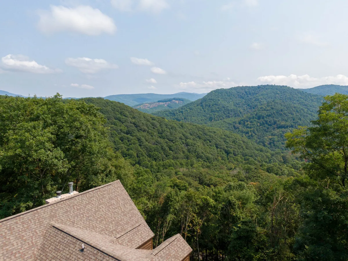 A sweeping view of a mountain range and dense forest beneath a clear sky. The scene is tranquil yet inspiring, representing the wider High Country terrain that guests can explore and enjoy.